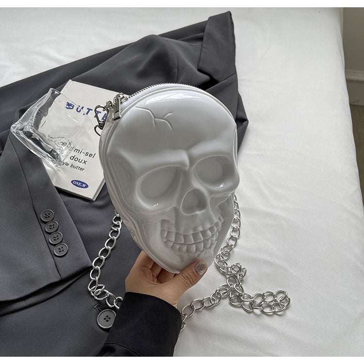 White silicone women's fashion chain bag shaped like a skull with silver chain strap on black blazer background