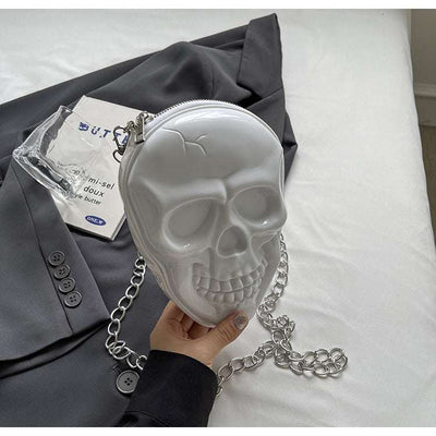 White silicone women's fashion chain bag shaped like a skull with silver chain strap on black blazer background