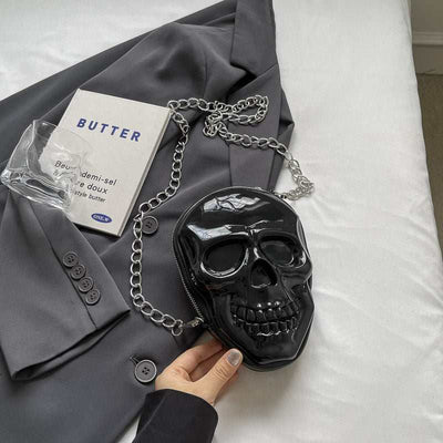 Black silicone women's fashion chain bag shaped like a skull with a silver chain strap on a gray blazer