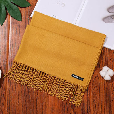 Mustard yellow soft cashmere women scarf shawl with fringe on wooden surface