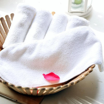 White microfiber washable baby diaper absorbent pad in a basket with a pink petal on top