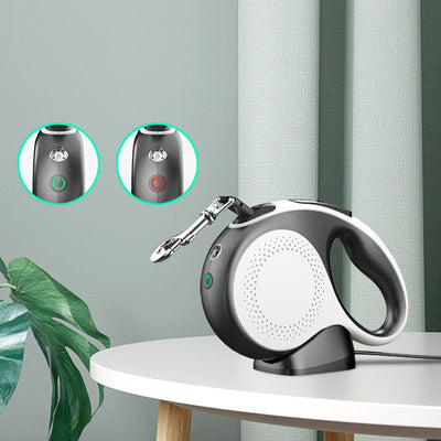 Black and white pet automatic retractable leash with rechargeable battery and built-in light on a charging stand on a white table