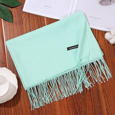 Mint green cashmere women scarf shawl with fringed edges on wooden table