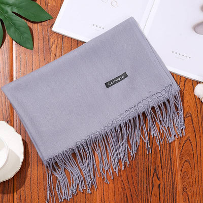 Soft gray cashmere women scarf shawl with fringed edges on wooden table