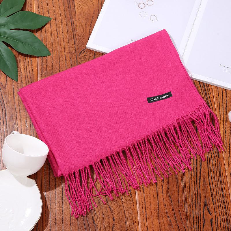 Pink cashmere women scarf shawl with fringed edges on wooden surface