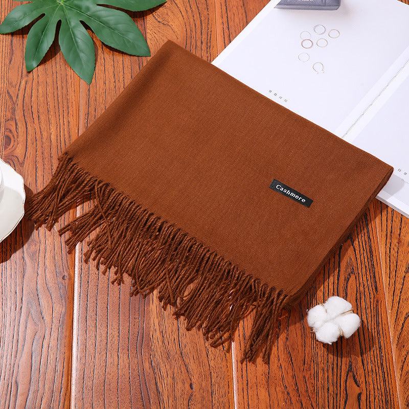 Brown cashmere women scarf shawl with fringed edges on wooden surface