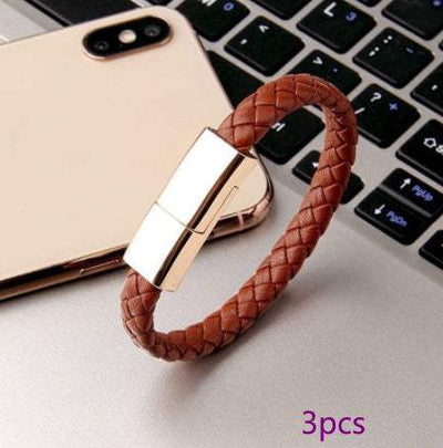 Brown braided leather USB charging cable bracelet with gold clasp on laptop keyboard
