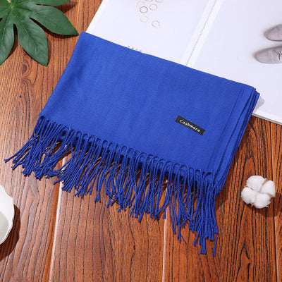Blue cashmere women scarf shawl with fringed edges on wooden surface
