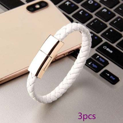 White braided leather USB charging bracelet with gold clasp on laptop keyboard