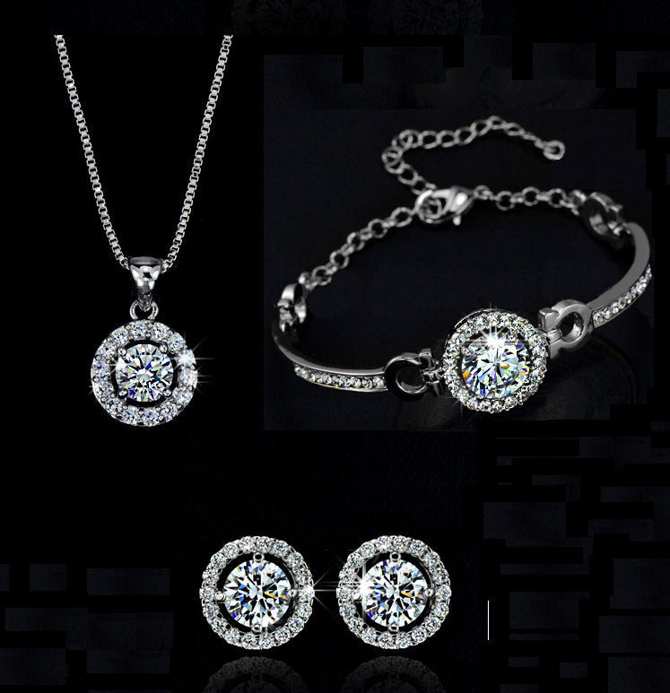 Silver alloy jewelry set with diamond-like round pendant necklace, matching bracelet, and stud earrings on black background