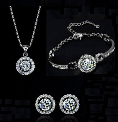 Silver alloy jewelry set with diamond-like round pendant necklace, matching bracelet, and stud earrings on black background