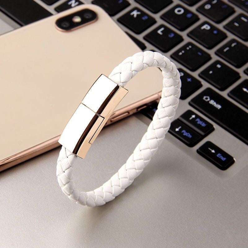 White braided leather USB charging bracelet with gold zinc alloy clasp on laptop keyboard and smartphone background