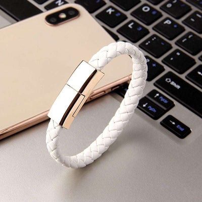 White braided leather USB charging bracelet with gold zinc alloy clasp on laptop keyboard and smartphone background