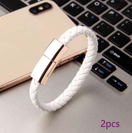 White braided leather USB charging cable bracelet with gold zinc alloy clasp near smartphone and keyboard