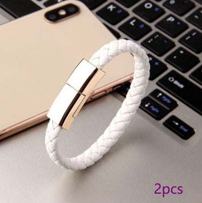 White braided leather USB charging cable bracelet with gold zinc alloy clasp near smartphone and keyboard