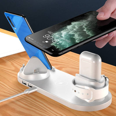 6 in 1 wireless charger dock station charging multiple devices including iPhone, smartwatch, and wireless earbuds on a wooden surface