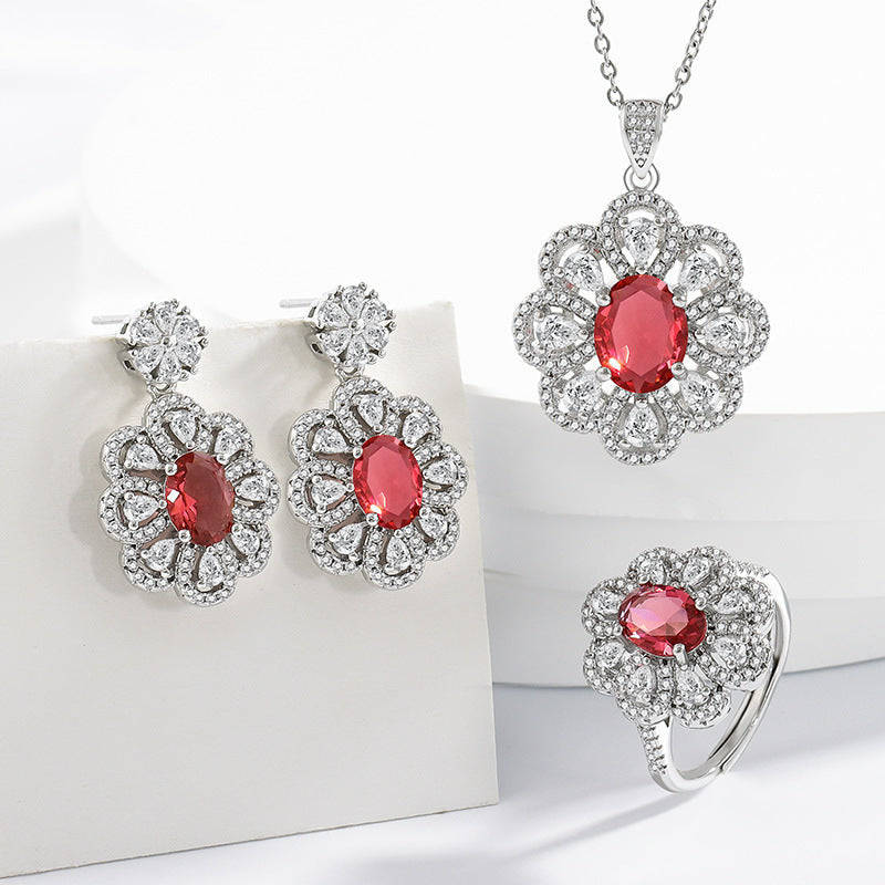 Bride jewelry earrings and necklace set with red oval gemstones and surrounding clear zircon crystals in floral design
