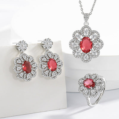 Bride jewelry earrings and necklace set with red oval gemstones and surrounding clear zircon crystals in floral design