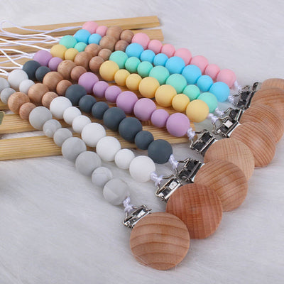 Set of colorful baby products pacifier clips with silicone beads and wooden clips on a white surface