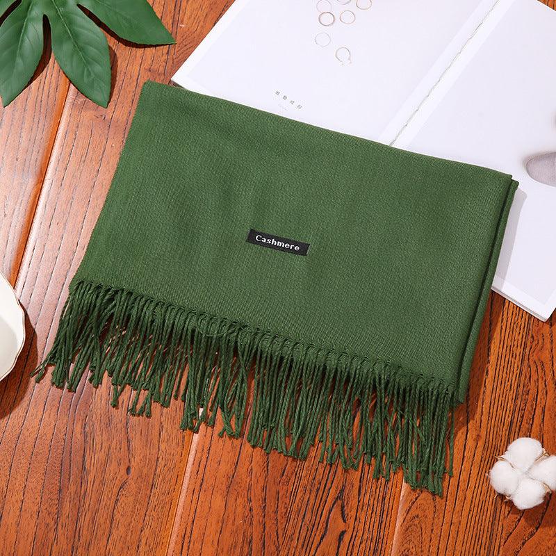 Green cashmere women scarf shawl with fringed edges on wooden surface