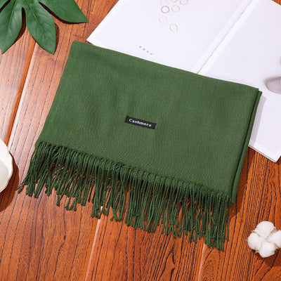 Green cashmere women scarf shawl with fringed edges on wooden surface
