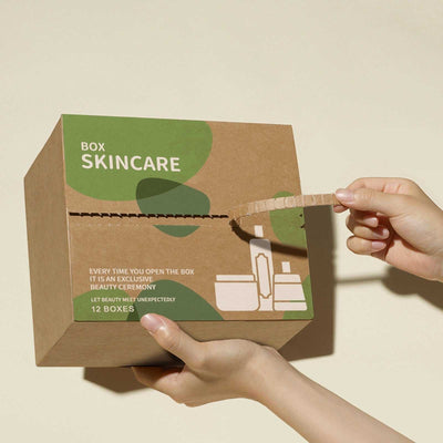 Hand holding a brown cardboard skincare box labeled "Skincare Box" with green design accents.