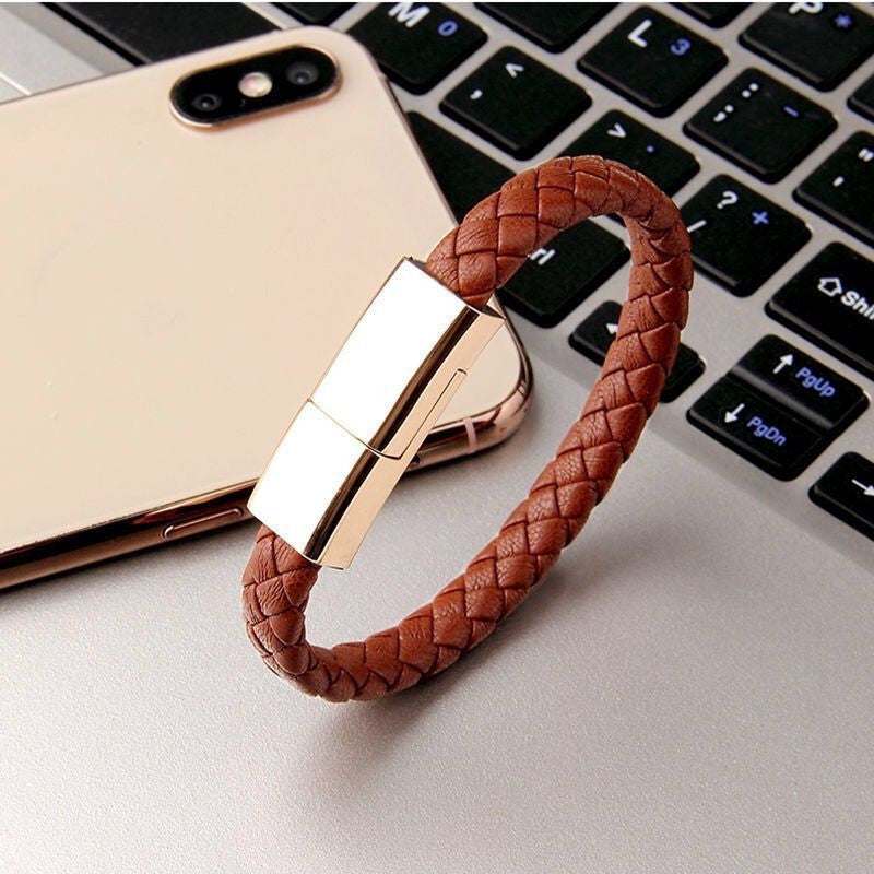 Brown braided leather bracelet charger USB charging cable with zinc alloy clasp next to a smartphone and keyboard