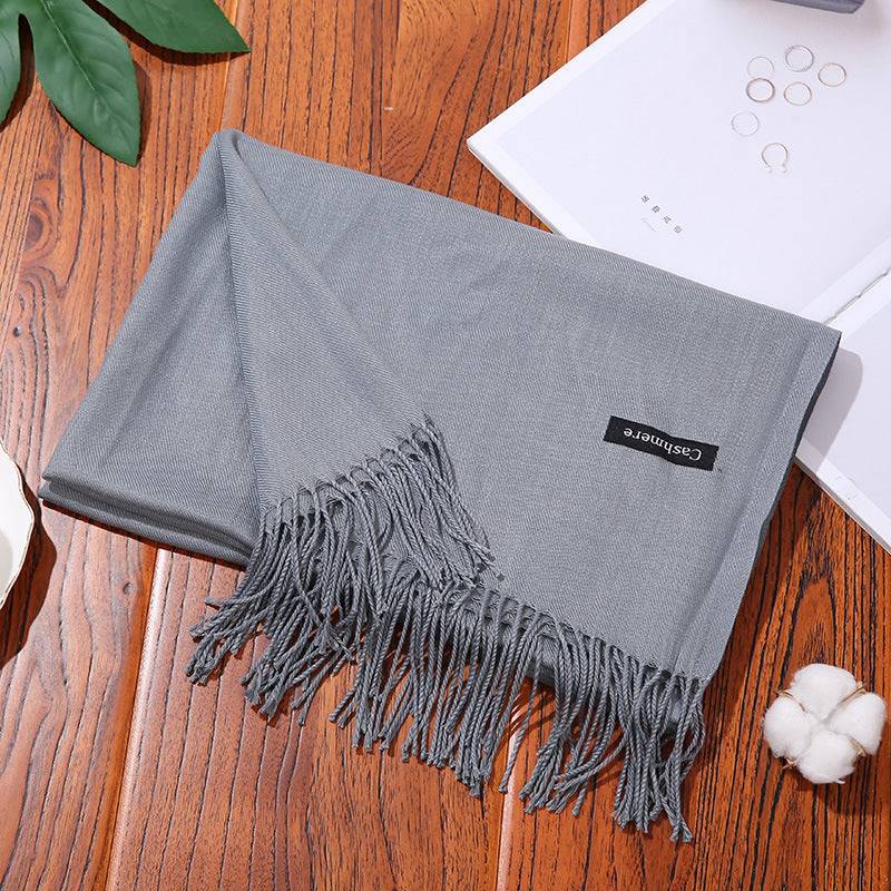 Soft gray women scarf shawl with fringe edges on wooden table