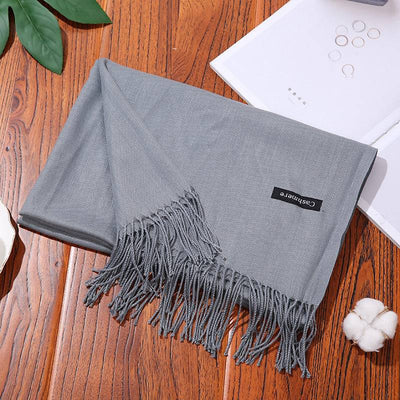Soft gray women scarf shawl with fringe edges on wooden table